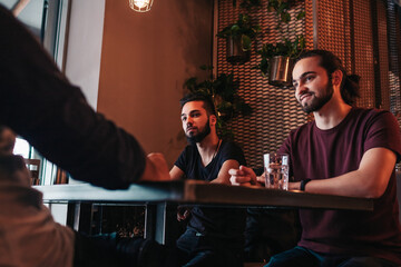 Group of mixed race young men talking and laughing in lounge bar. Multiracial friends having fun in cafe. Guys hangout