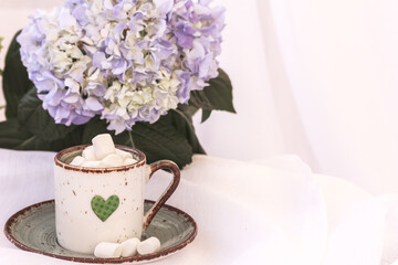 Green cup with, cocoa, coffee with marshmallows, Hortensia, hydrangea flower on white background. Drinking coffee with love. Copy space right, mock up