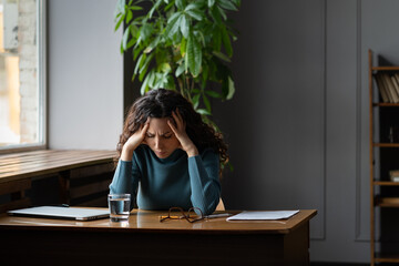 Exhausted stressed woman sitting at office desk with closed laptop tired of overwork, stress,...