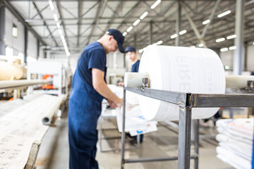Fototapeta premium Workers in a factory carry out technological processes on a conveyor line in protective overalls