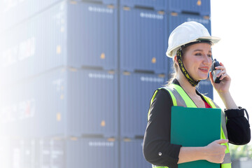 Confident woman engineer wearing white safety helmet 
working checking at container cargo harbor holding note pad and radio to loading containers for business Logistics import export shipping.