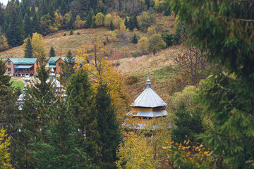 Small wooden church among foliage of trees in mountain valley