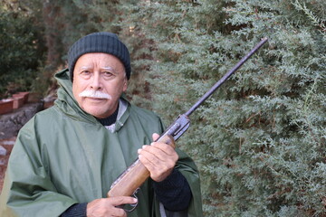 Senior hunter holding weapon in forest