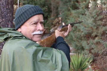 Senior hunter holding weapon in forest