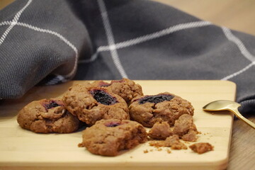 Chocolate cookies with berries and crumbs are lying on a wooden board