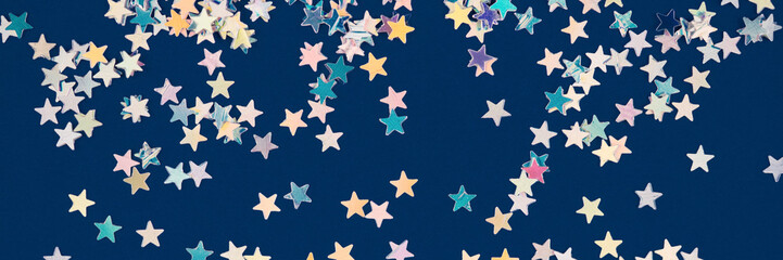 Festive background with holographic sparkling stars confetti on dark blue background. Christmas,...
