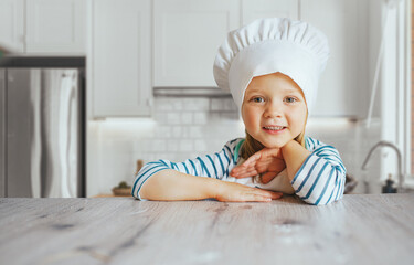 happy cute little kid girl wear chef uniform and cooking a birthday cake