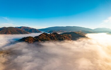 Fog among peaks of high autumn mountains with forests
