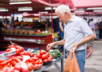 retired european man buying tomatoes in market