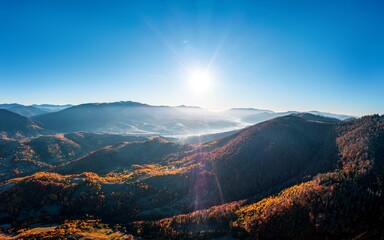 High mountain peaks with yellowed forest under bright sun