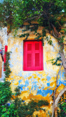 Old rustic house window with red wooden shutters