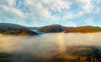 Thick layer of fog covering rainbow mountains with colorful trees