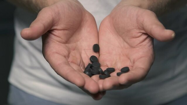 Man hands close up pouring activated carbon, taking medication. Health