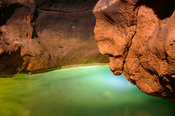 A cave with red walls and an underground lake