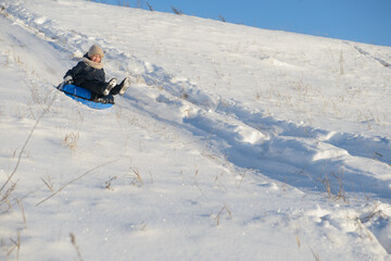 A girl rides an inflatable cheesecake from a snowy hill