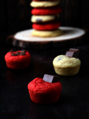 delicious cookies and cupcake cookies with red and yellow color  vanilla and red velvet flavor and black background with chocolate chips 
