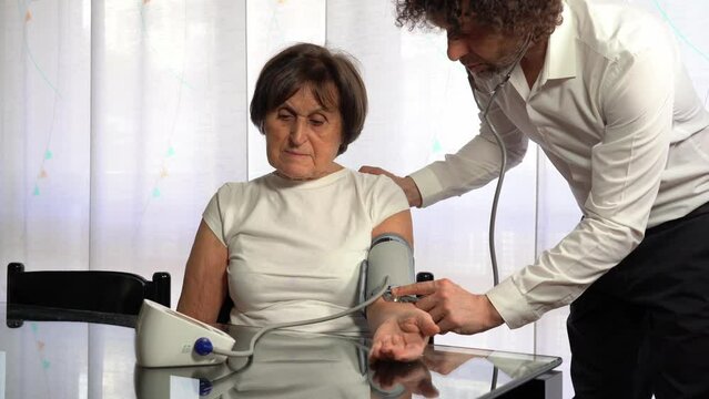 70 year old old lady woman tests blood pressure at home - private doctor visit in apartment  during Covid-19 Coronavirus lockdown epidemic
