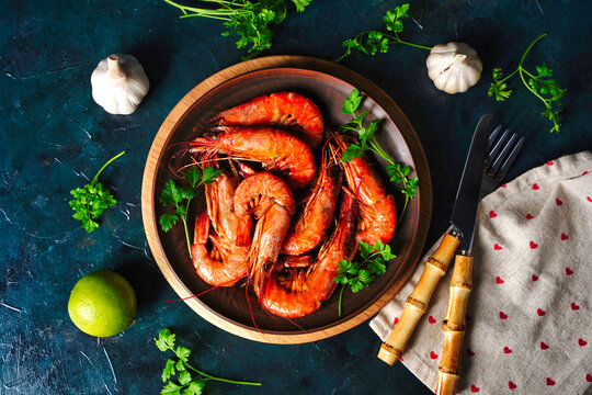 Cooked shrimp and langoustines, king prawns with lime, garlic and parsley. Grilled and fried on dark blue background