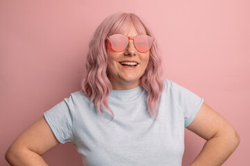 Portrait of stylish trendy woman in pink color glasses isolated over pink background