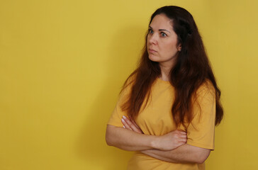 Obraz premium A beautiful woman in a yellow T-shirt with long hair in a state of bewildered surprise.
