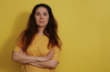 Obraz premium Close up portrait of a surprised woman in a yellow t-shirt on a studio background.
