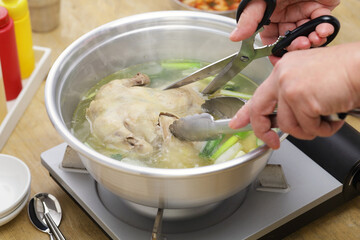 korean whole chicken soup hot pot, cutting whole chicken with scissors