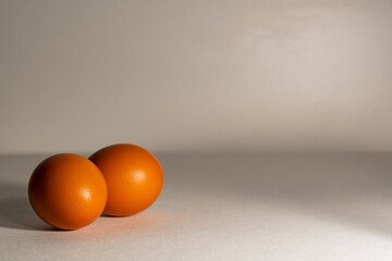Two chicken eggs are lying side by side, on a light background. Fresh chicken eggs, with a textured brown shell, on Easter eve.