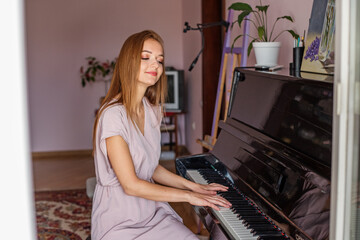 Young woman plays piano at home. Pianist is practicing before concert. Hobies and entertainment.