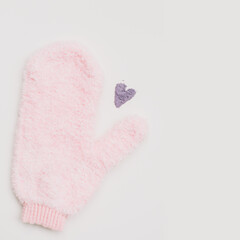 Minimal flat lay composition of massage mitten washcloth and a heart made of violet powder on a white background. Concept of zero waste