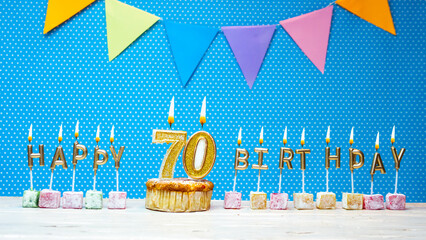 Happy birthday from number 70 candle letters on a blue background with white polka dot copy space....