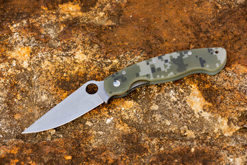 folder knife lying open on stones