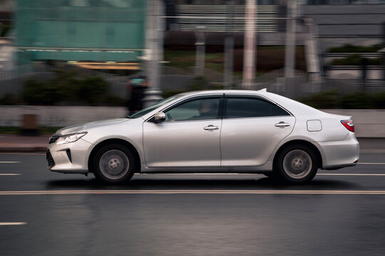 Fast moving Toyota Camry XV50 on the city road. Silver sedan with man driving. Used auto in fast motion with blurred background. Speeding in the city concept