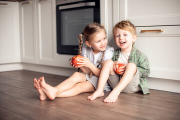 Healthy food at home. Happy two cute children: girl and boy eating healthy fruits red apples in the white kitchen. Healthy food baby dieting concept. selective focus © katyagorphoto