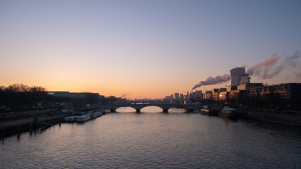 Bridge over the Seine at sunrise in Paris, with a smoke at the horizon