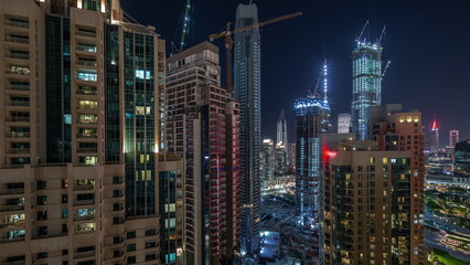 Fototapeta na wymiar Cranes working on big constraction site works of new skyscrapers night timelapse