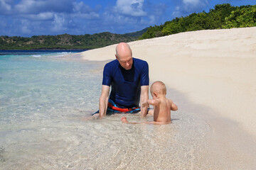 Father with a baby playing at the beach, White Island, Grenada.