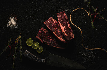 corte de res  CABRERIA  sobre laja de piedra  con decoración como sal, pimienta limón, chile de árbol  , romero y un cuchillo  