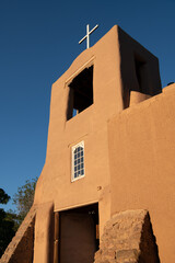Naklejka premium Adobe bell tower and white cross of San Miguel Chapel in Santa Fe, New Mexico