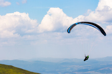 paragliding above the mountain valley. extreme outdoor sports. adventure and travel concept. clouds on the sky in summer