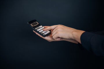 Hand holding calculator on black background