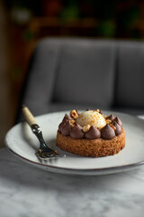 Chocolate caramel pie with nuts in a white plate on a marble background