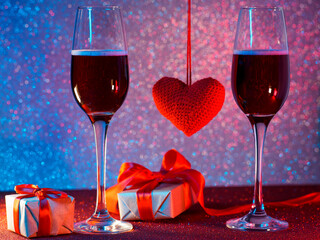 Happy Valentine's Day greeting card. Two glasses of sparkling wine, a neon bokeh background, gift boxes and a red heart