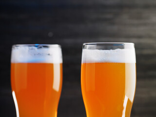 two glasses of beer on a dark wooden background