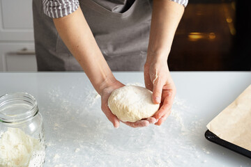 A woman is in the kitchen baking bagels with jam. Sweet pastry with your own hands. Woman kneading dough for baking.