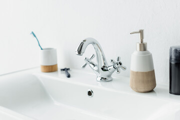 Fototapeta na wymiar shaving foam, liquid soap, safety razor and toothbrush on white sink with faucet.
