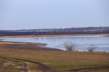 Bank of the river in early spring, the water is present unmelted ice. A small steppe river in late winter or early spring