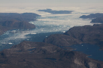 poszarpane surowe i skaliste wybrzeże Grenlandii oraz morze pokryte krą lodową widziane z samolotu z dużej wysokości - 482907652