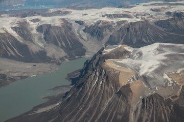 górzyste wybrzeże grenlandii pokryte topniejącym śniegiem i lodem oraz morze widziane z samolotu