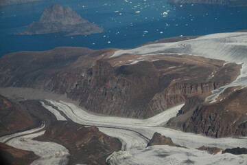 górzyste wybrzeże grenlandii pokryte topniejącym śniegiem i lodem oraz morze pokryte krą widziane z samolotu - obrazy, fototapety, plakaty