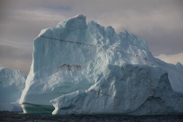 duże góry lodowe o różnych kształtach na morzu w pochmurny dzień - 482907819